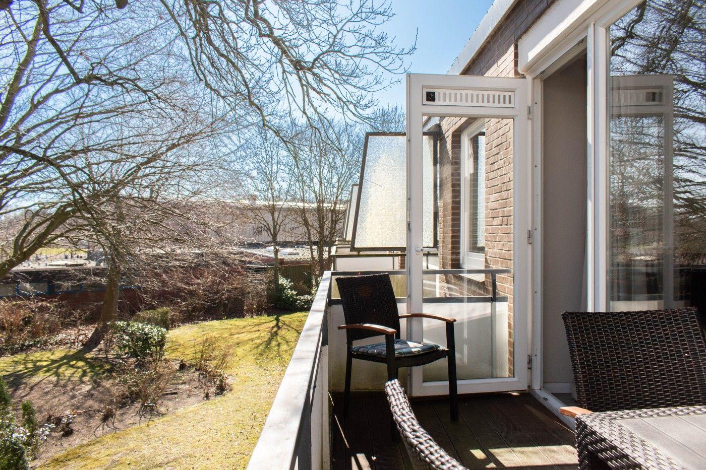 Terrasse mit Sitzgelegenheiten und Blick auf Garten und Bäume.