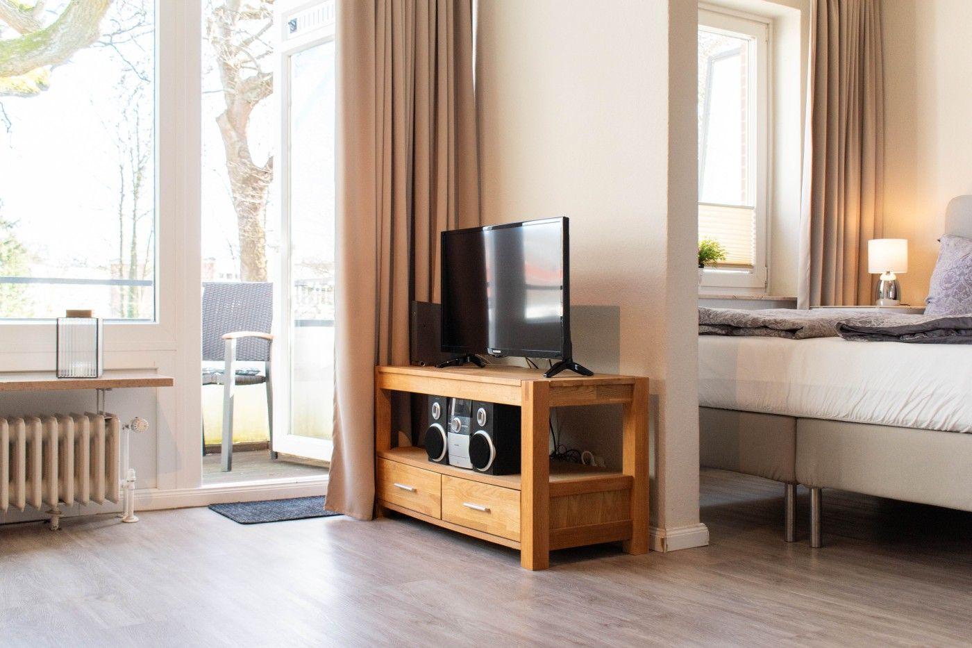 Schlafzimmer mit TV, Bett und Balkonzugang.