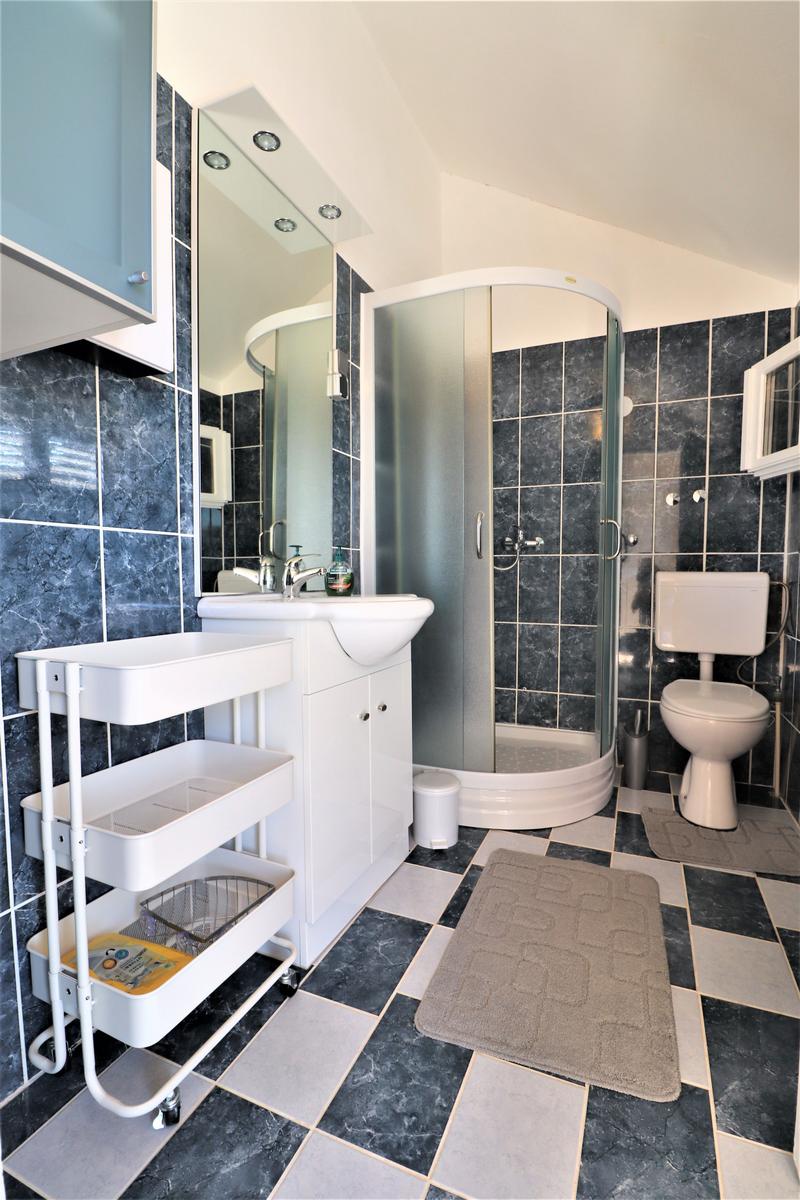 Badezimmer mit Dusche, Toilette und Waschbecken. Fliesenboden und Wandfliesen.