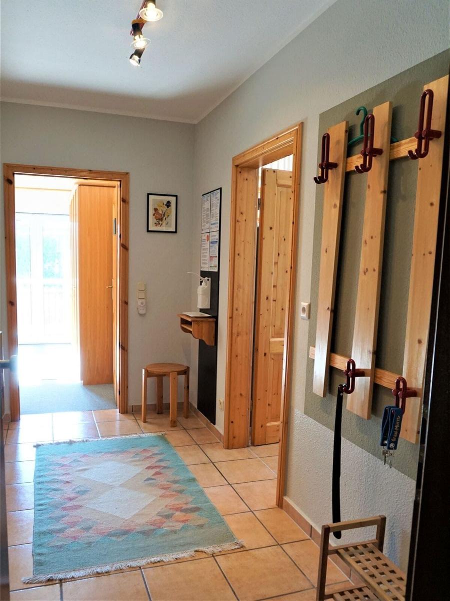 Flur mit Holztüren, Teppich und Kleiderhaken an der Wand.
