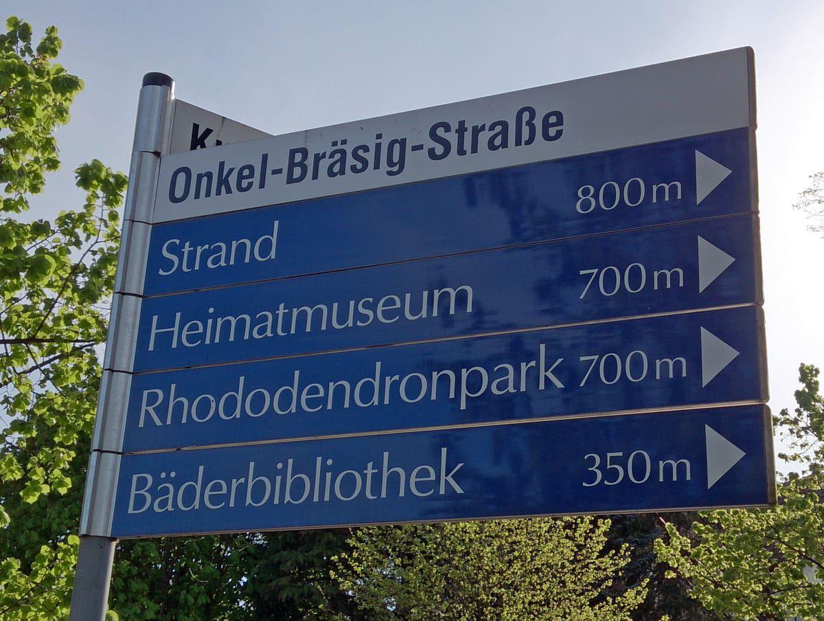 Schild zeigt Entfernungen zu Strand, Museum, Park und Bibliothek.