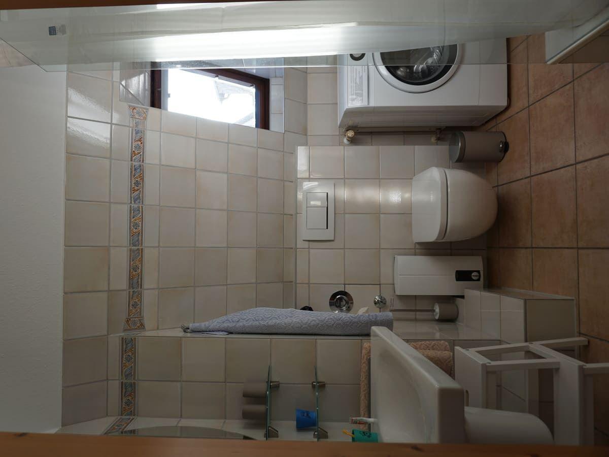 Badezimmer mit Waschmaschine, WC und Badewanne.