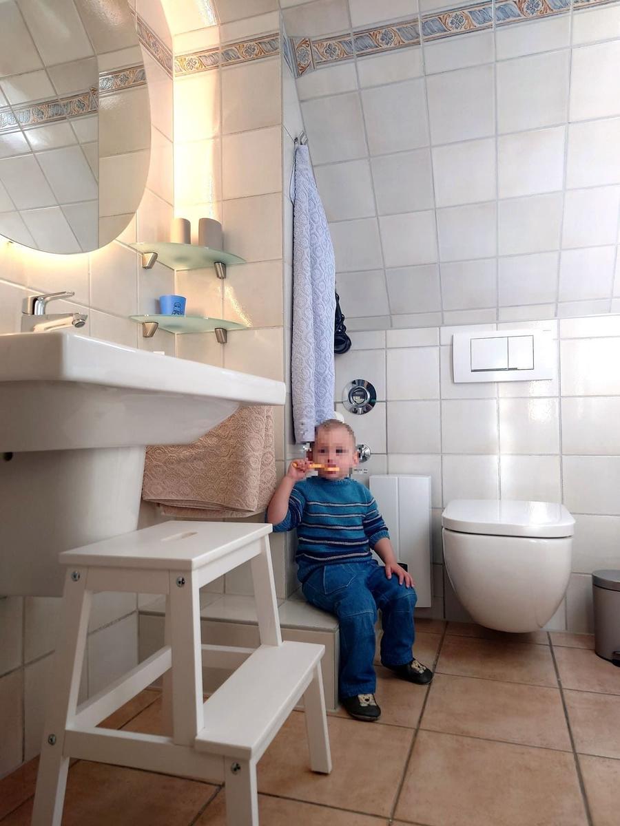 Badezimmer mit Waschbecken, Toilette und Kindersitzstuhl.