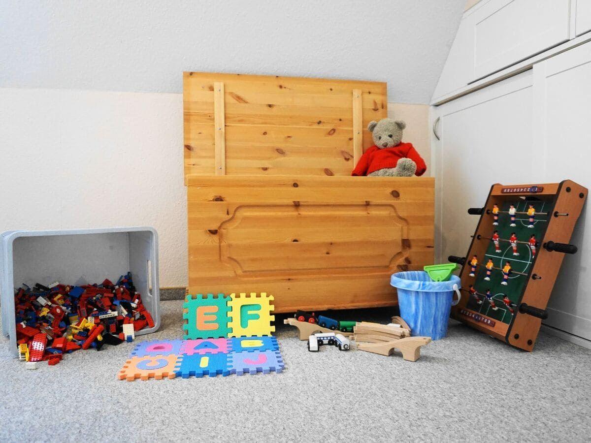 Kinderzimmer mit Holztruhe, Spielzeug und Falttisch.