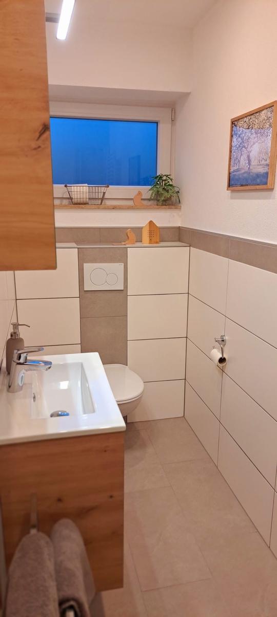 Badezimmer mit Waschbecken, Toilette und Fenster