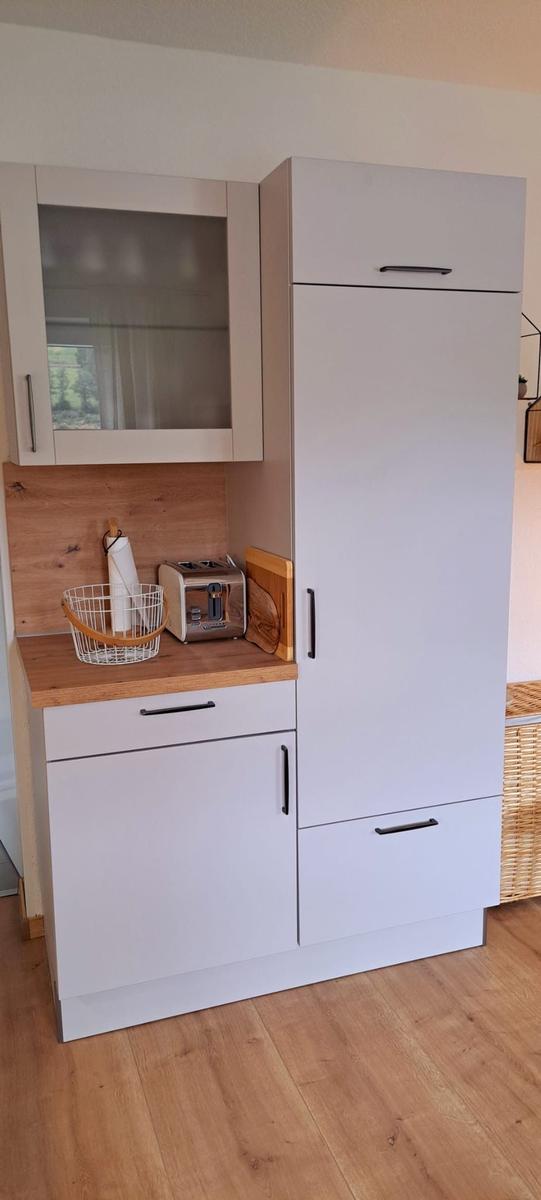 Küchenbereich mit weißen Schränken, Holzoberfläche und Toaster.