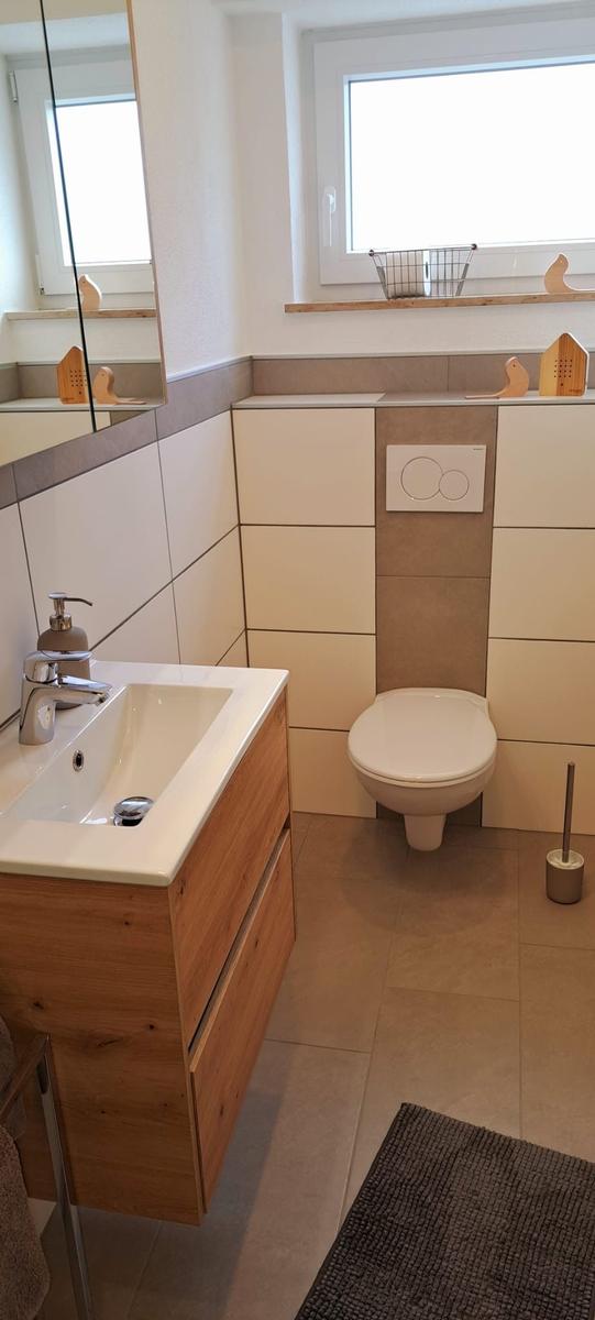 Badezimmer mit Waschbecken, Toilette und Fenster