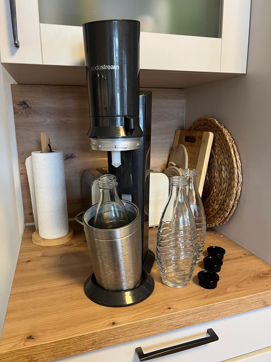 Sodastream-Gerät mit Gläsern und Zubehör auf Küchenarbeitsfläche.