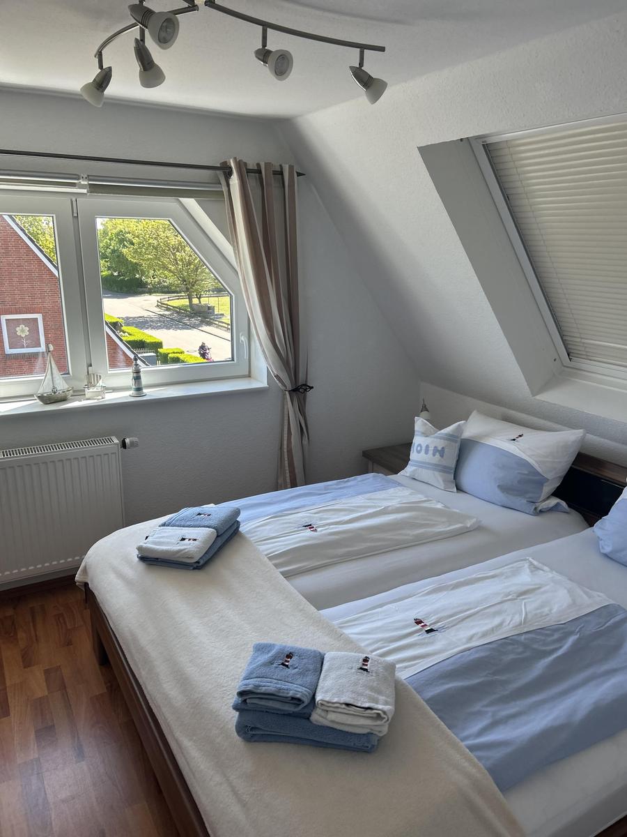Zimmer mit zwei Betten, Dachfenster und Blick auf Garten.