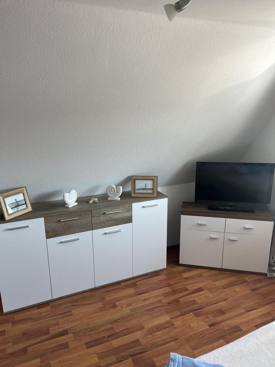 Schlafzimmer mit Holzboden, Schrank und Fernseher auf einem Möbelstück.