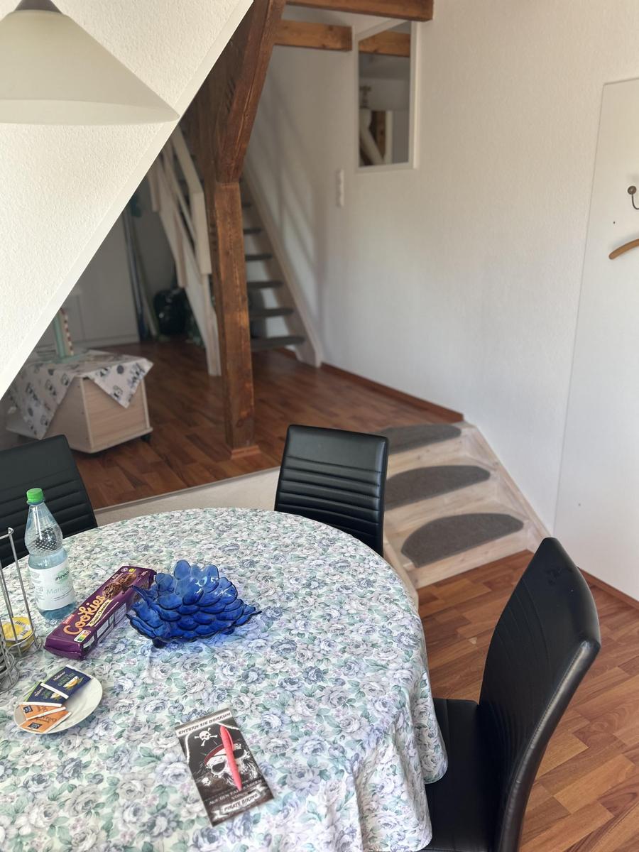Rundtisch mit Tischdecke, Stühle und Treppenaufgang im Hintergrund.