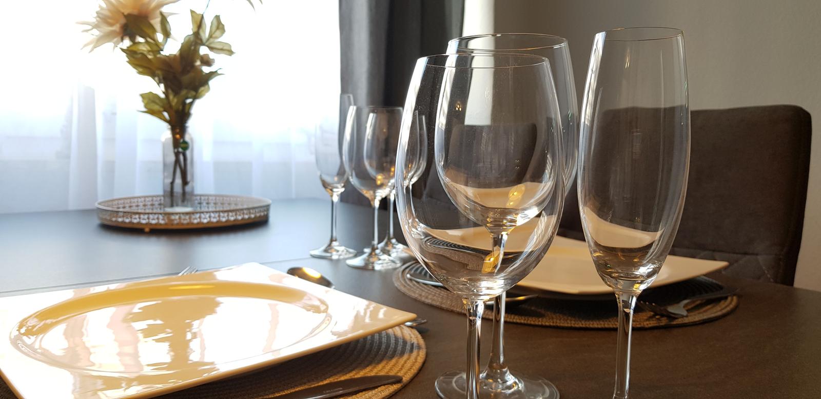 Geschirr und Gläser auf einem Tisch mit Platzsetzung und Blumenvase.