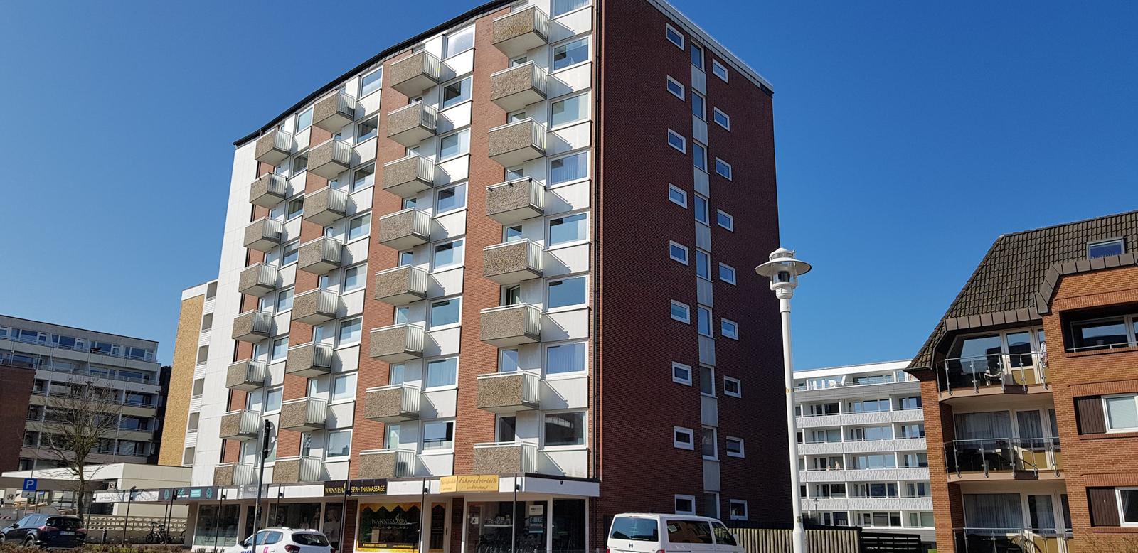 Hochhaus mit Balkonen und Geschäften im Erdgeschoss.