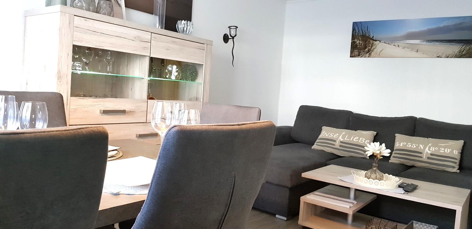 Wohn- und Essbereich mit Sofa, Tisch und Sideboard.