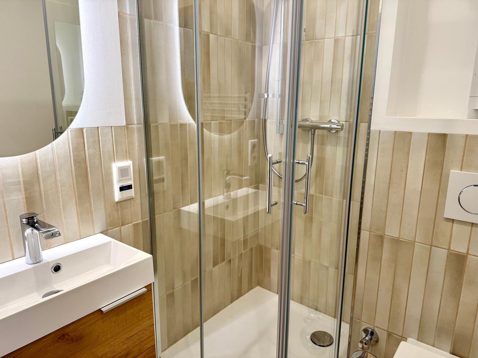 Badezimmer mit Dusche, Waschbecken und Spiegel