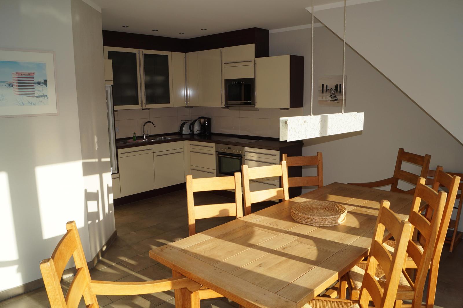 Küche und Essbereich mit Holztisch, Stühlen und Küchenschränken.