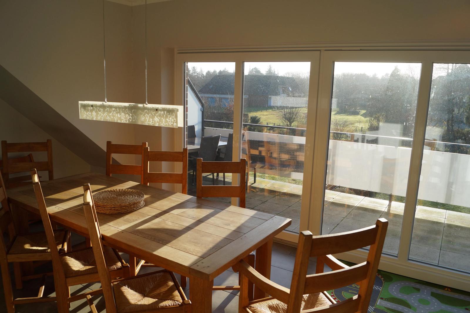 Essbereich mit Holztisch und Stühlen. Durchgang zur Terrasse mit Gartenblick.