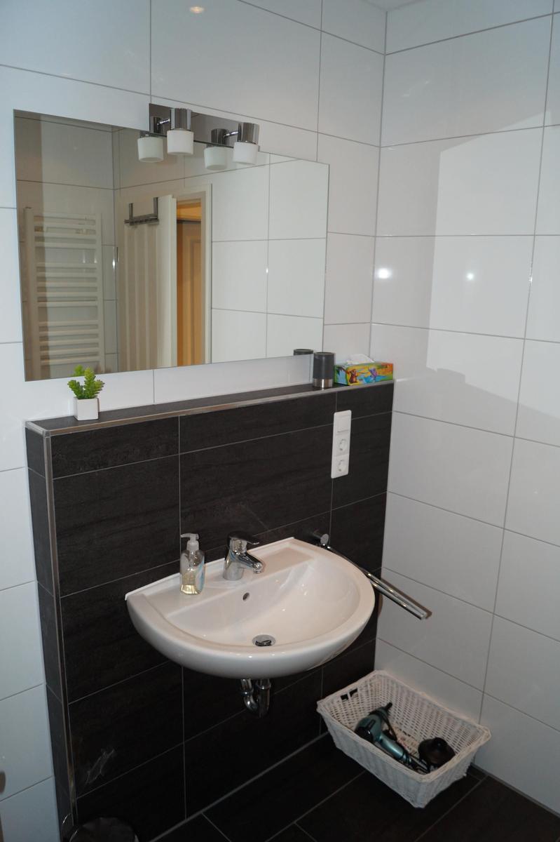 Bad mit Waschbecken, Spiegel und Duschbereich