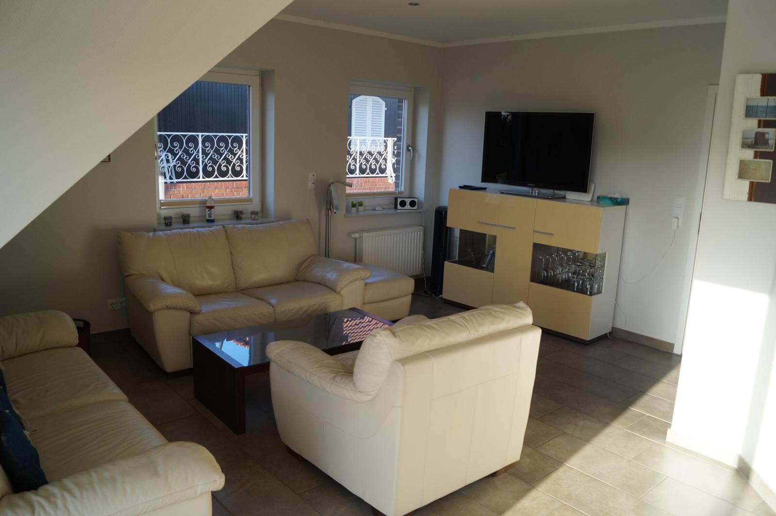 Wohnzimmer mit Ledersofa, Sessel, TV und Glaswand