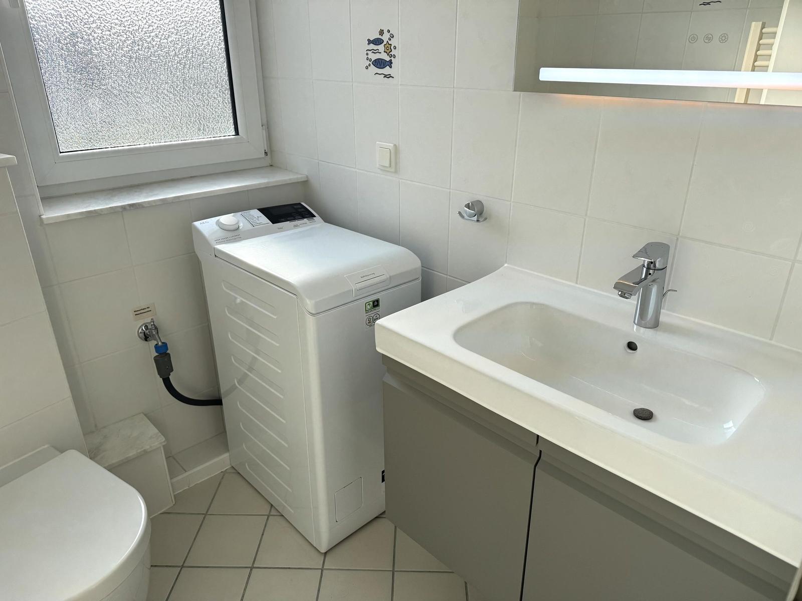 Badezimmer mit Waschmaschine, Waschtisch und Toilette