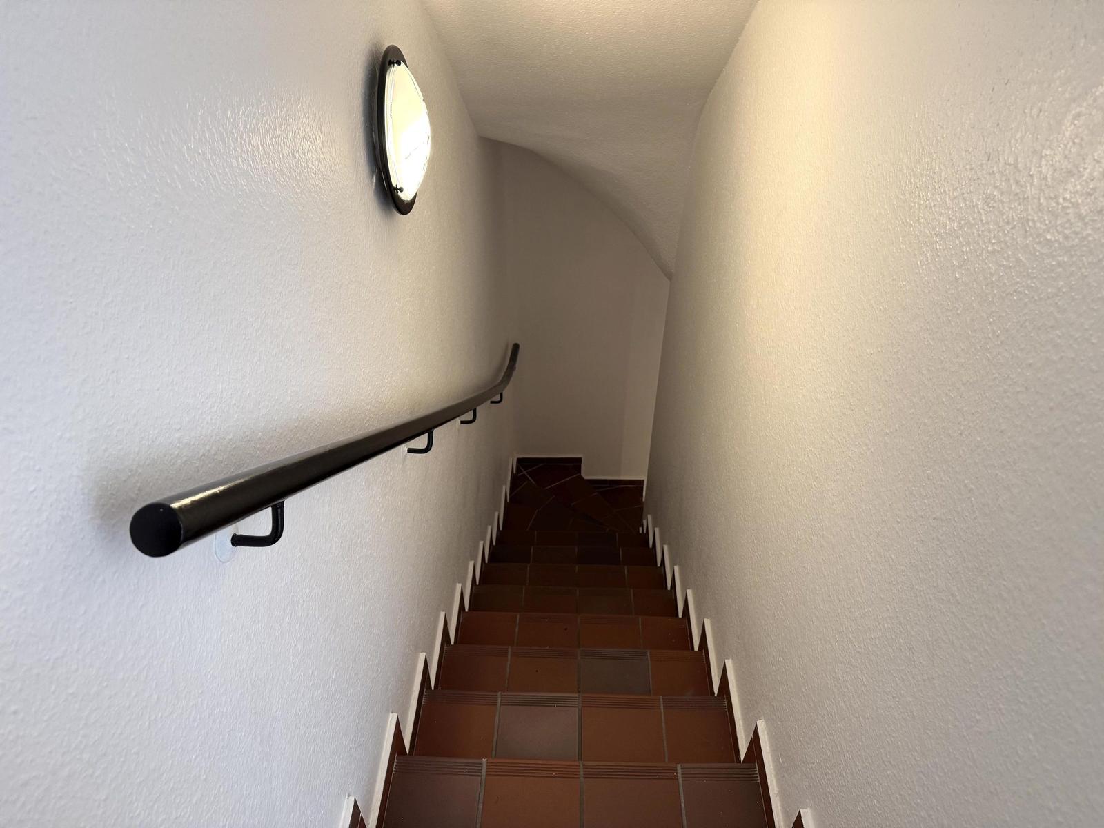 Treppenhaus mit dunkler Handlauf und runden Wanduhr