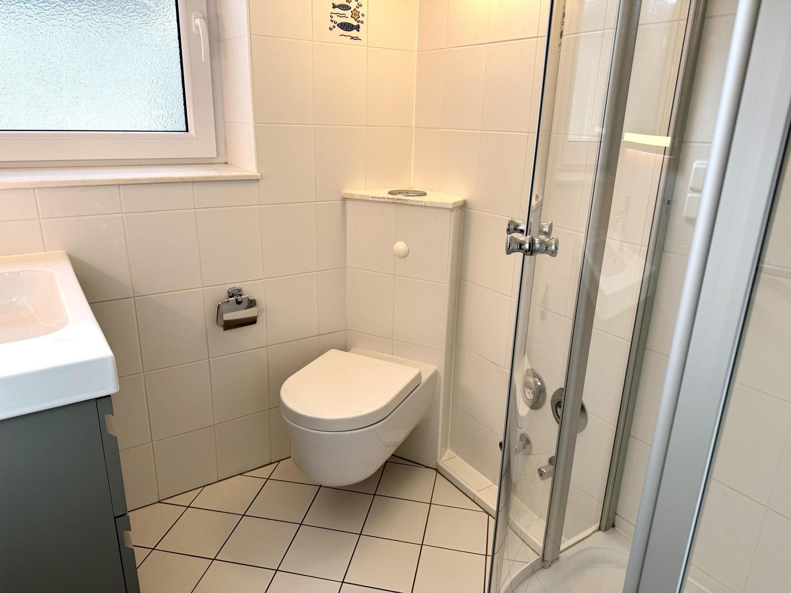 Badezimmer mit Dusche, Toilette und Waschbecken.