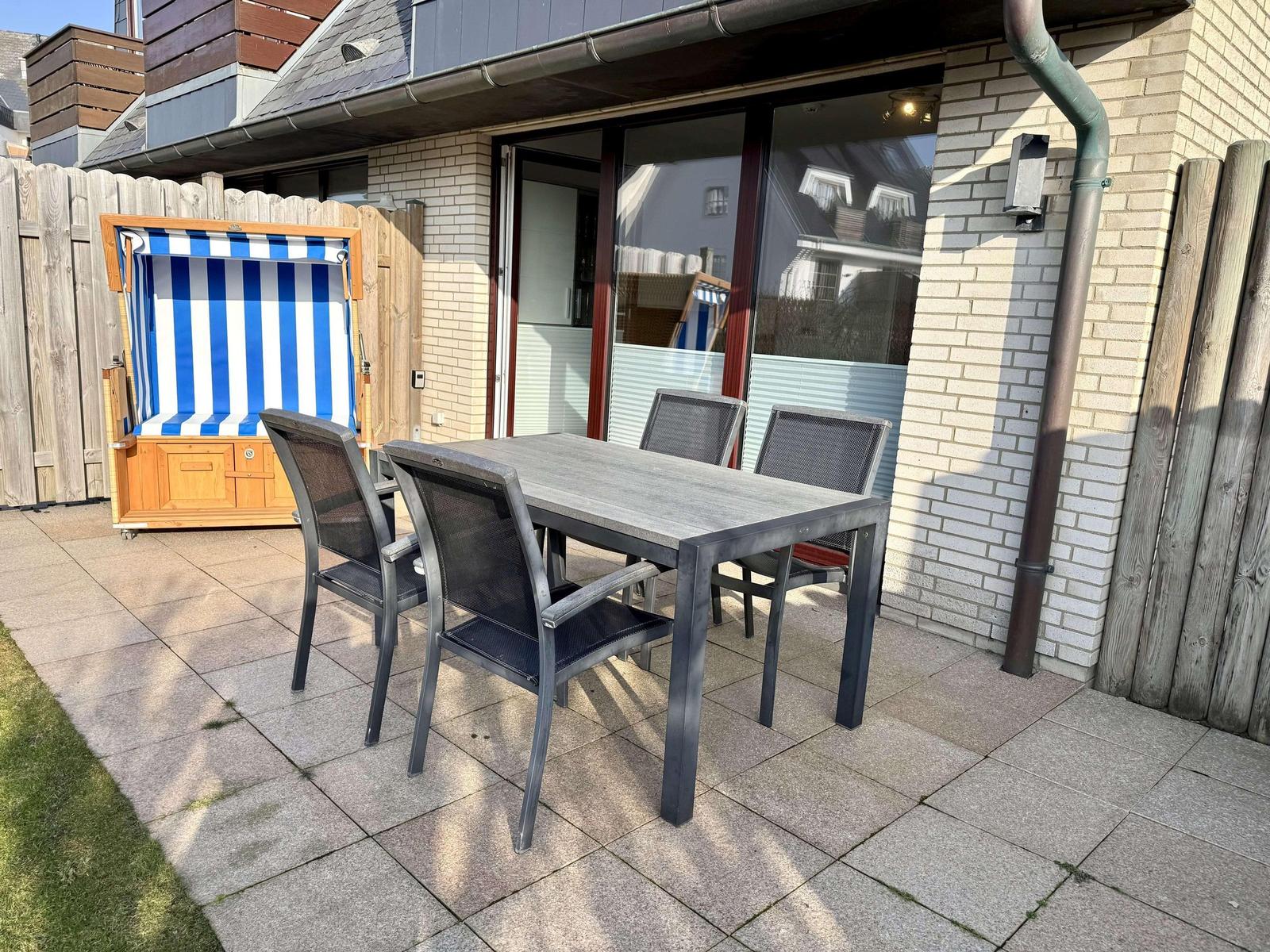 Terrasse mit Tisch und Stühlen sowie Strandkorb.
