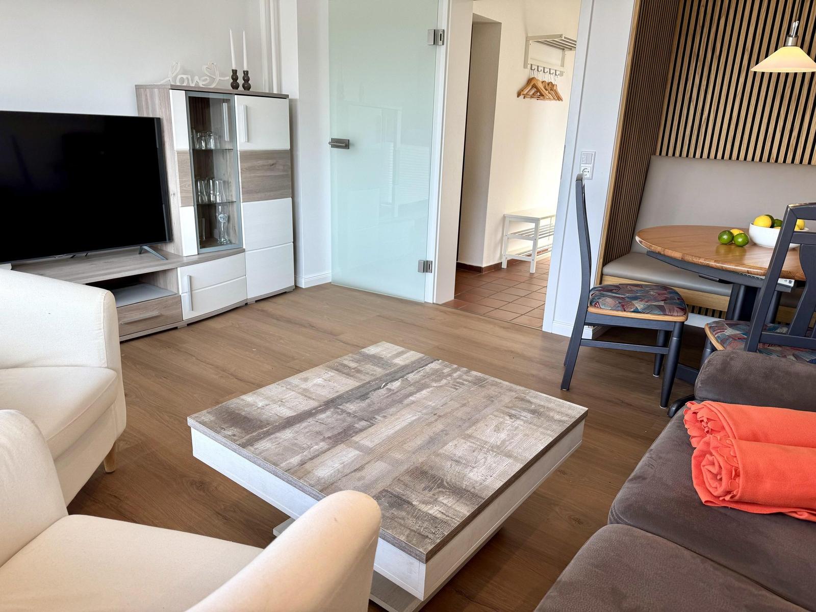 Wohn- und Essbereich mit Sofa, Couchtisch und Fernseher.