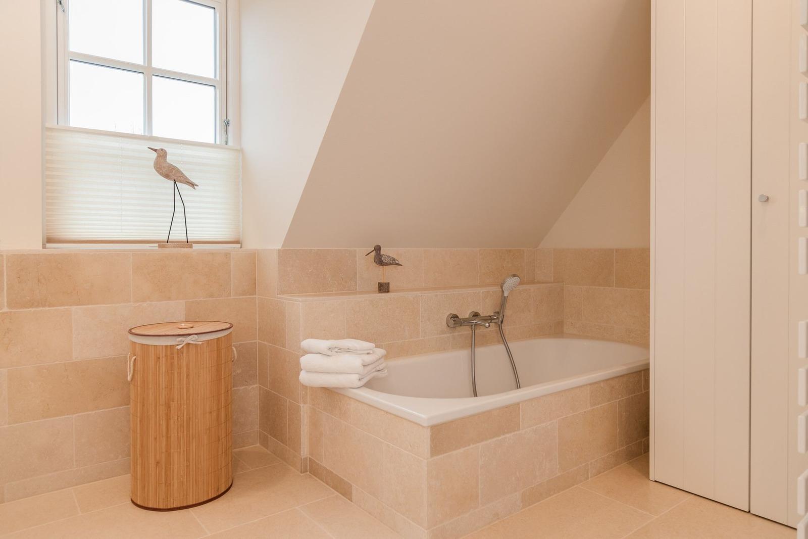 Bad mit Badewanne, Fenster und Holzwaschbecken.