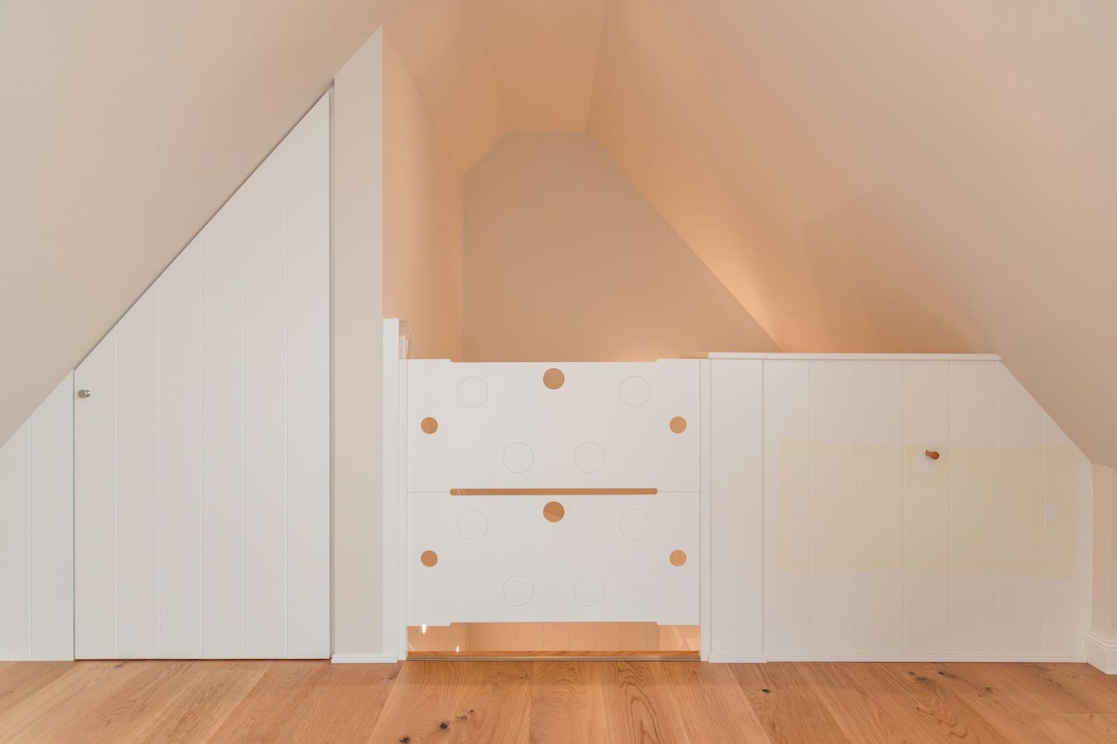 Dachschrägen Raum mit weißem Schrank und Holzboden