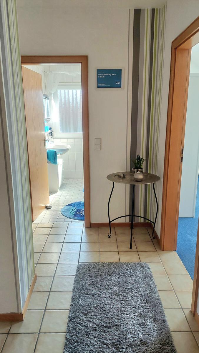 Flur mit Teppich, kleiner Tisch und Blick in Bad und Schlafzimmer.