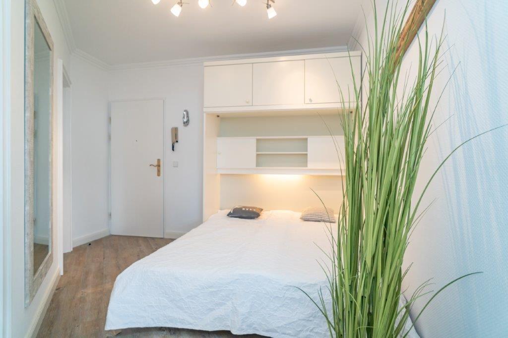 Schlafzimmer mit Bett, Schrank und Pflanze
