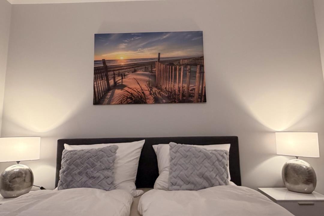 Schlafzimmer mit Bett, zwei Nachttischen und Wandbild an der Wand.