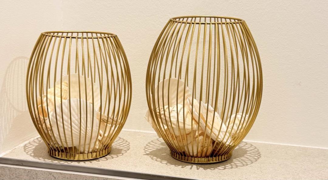 Zwei goldfarbene Körbe mit Muscheln stehen auf einer Ablagefläche.