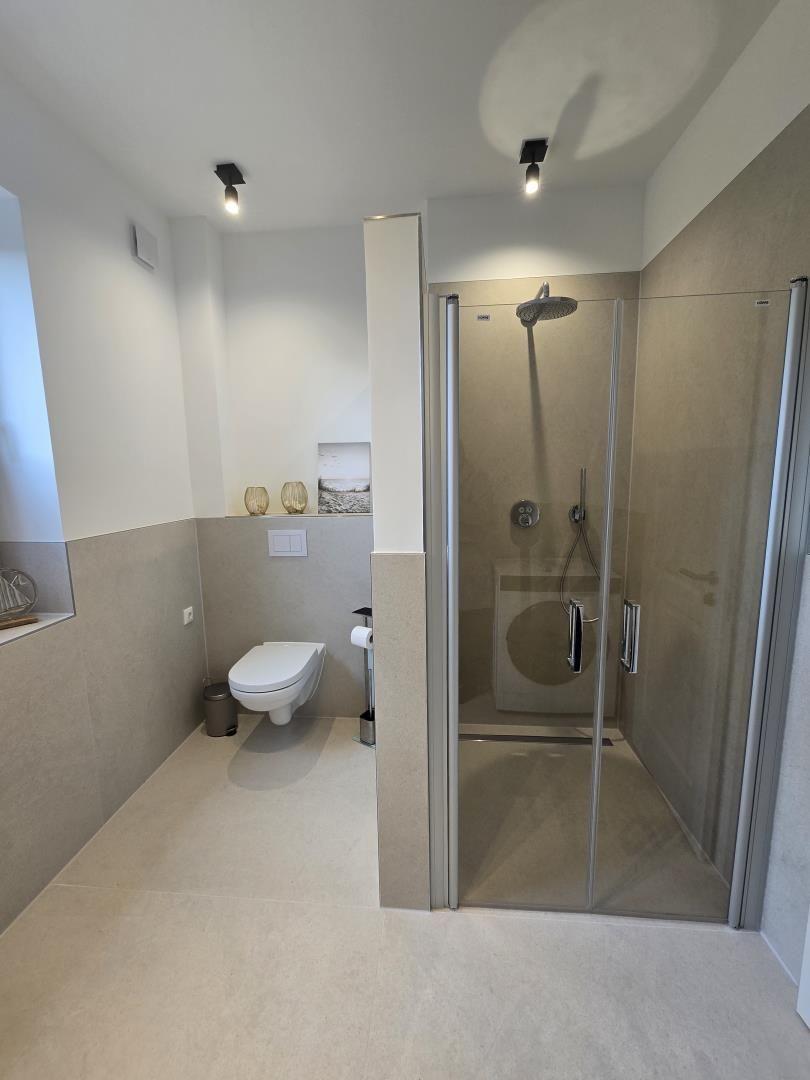 Badezimmer mit Dusche, Toilette und Fenster