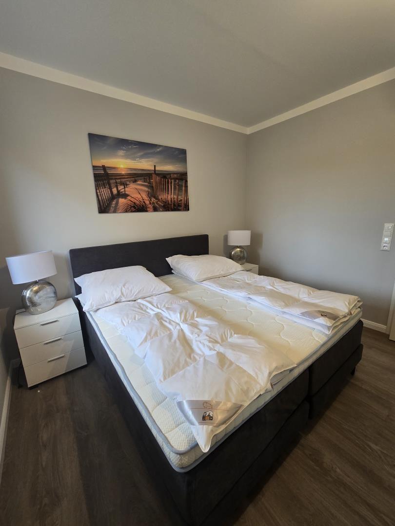 Schlafzimmer mit Doppelbett, zwei Nachttischen und Wandbild.