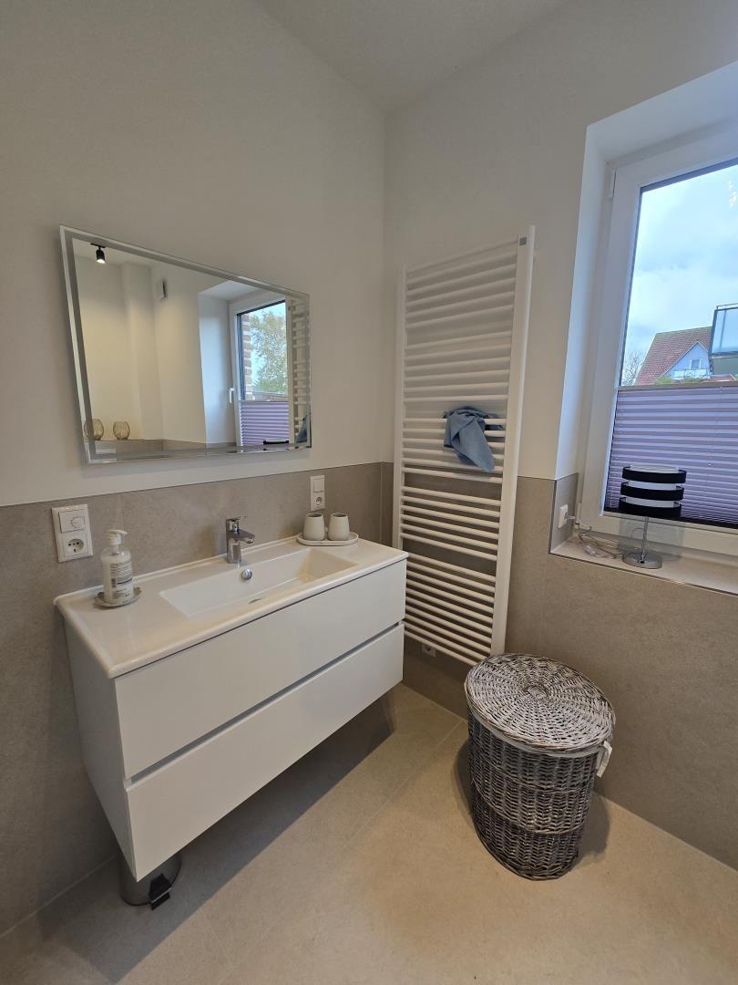 Badezimmer mit Waschbecken, Spiegel und Fenster