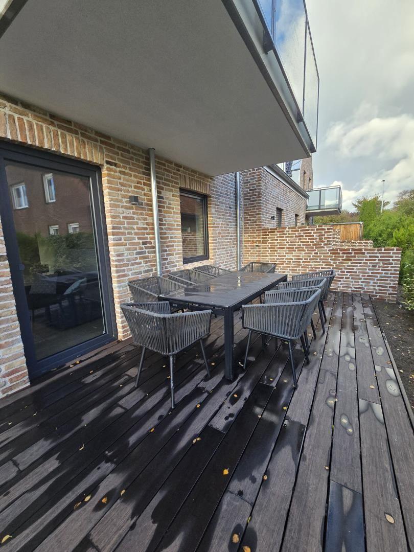 Terrasse mit Tisch und Stühlen, angrenzend an ein Haus mit Backsteinmauer.
