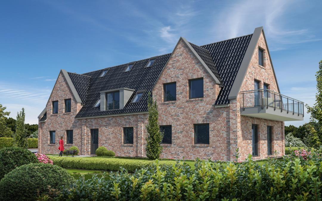 Modernes Haus mit Ziegelfassade und Balkon. Garten mit Beete und Bäumen.