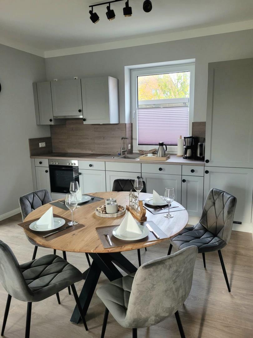 Runde Tisch mit Stühlen und Küchenbereich mit Fenster.