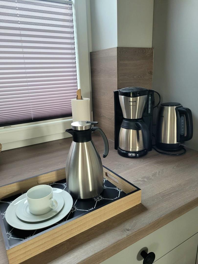 Kaffeemaschine, Wasserkocher und Thermoflasche auf Küchenarbeitsfläche.