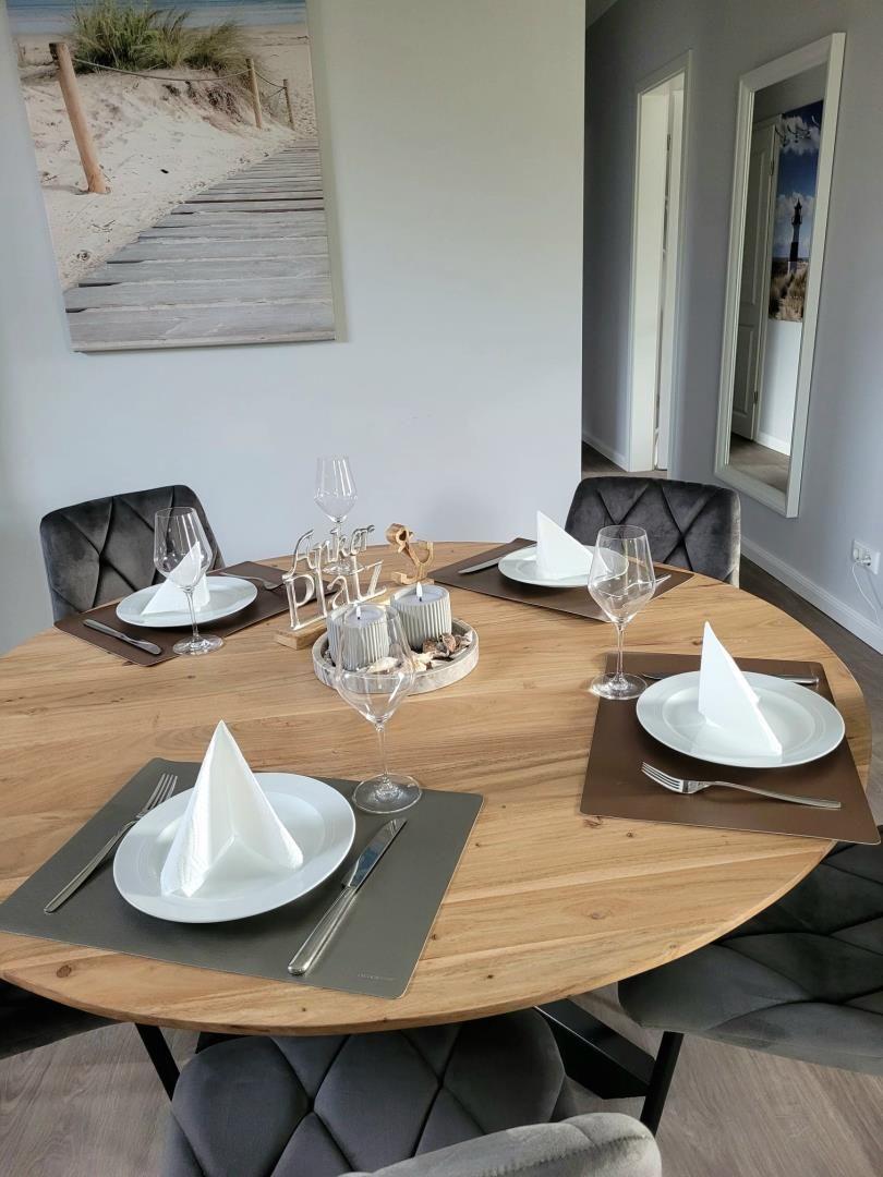 Runder Holztisch mit vier Stühlen und gedeckten Plätzen.