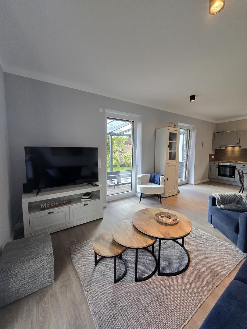 Wohnzimmer mit TV, Tisch, Sofa und Blick auf die Terrasse.