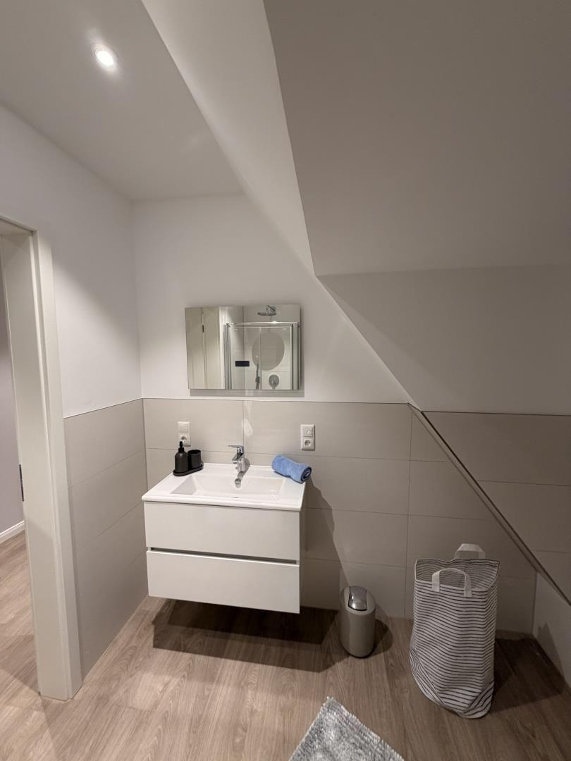 Badezimmer mit Waschbecken, Spiegel und Dusche unter Dachschräge