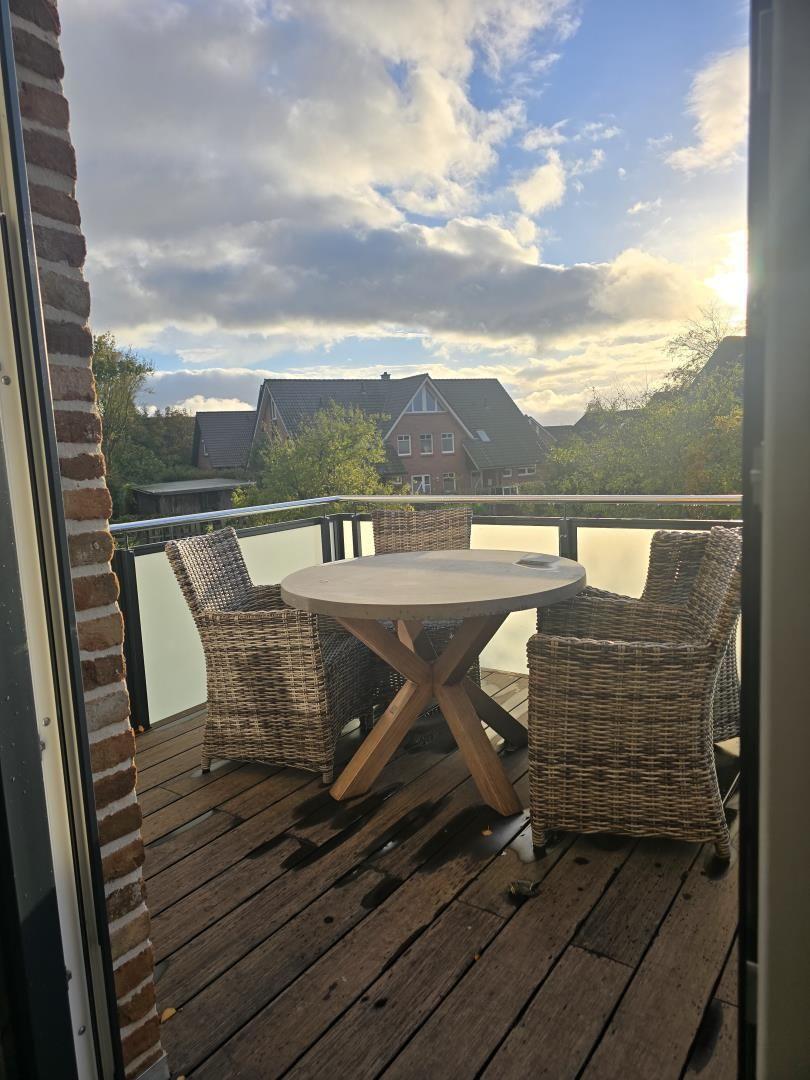 Terrasse mit Tisch und Stühlen, Blick auf Häuser und Bäume.