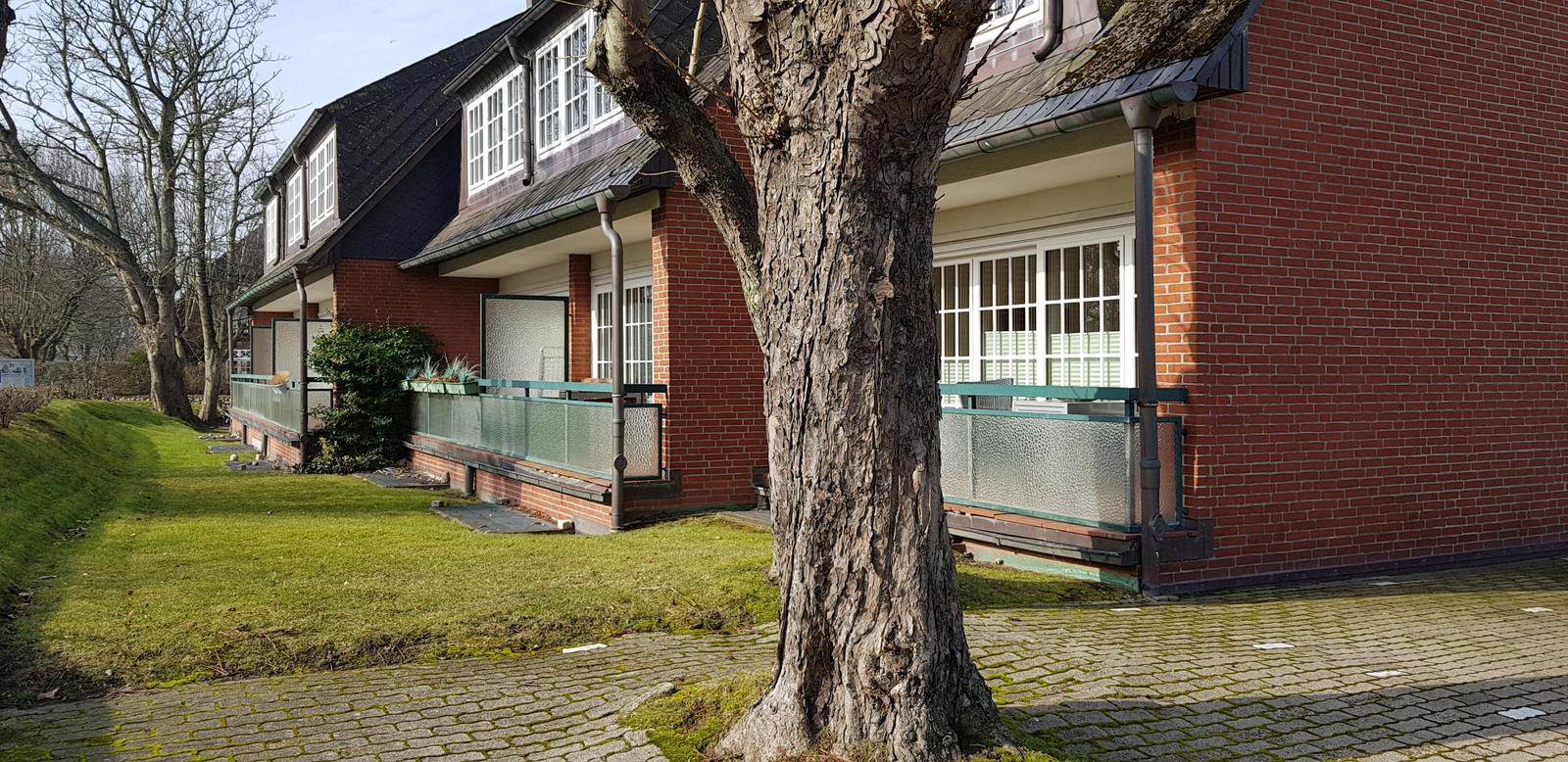 Rotes Backsteingebäude mit Balkon und grüner Rasenfläche.