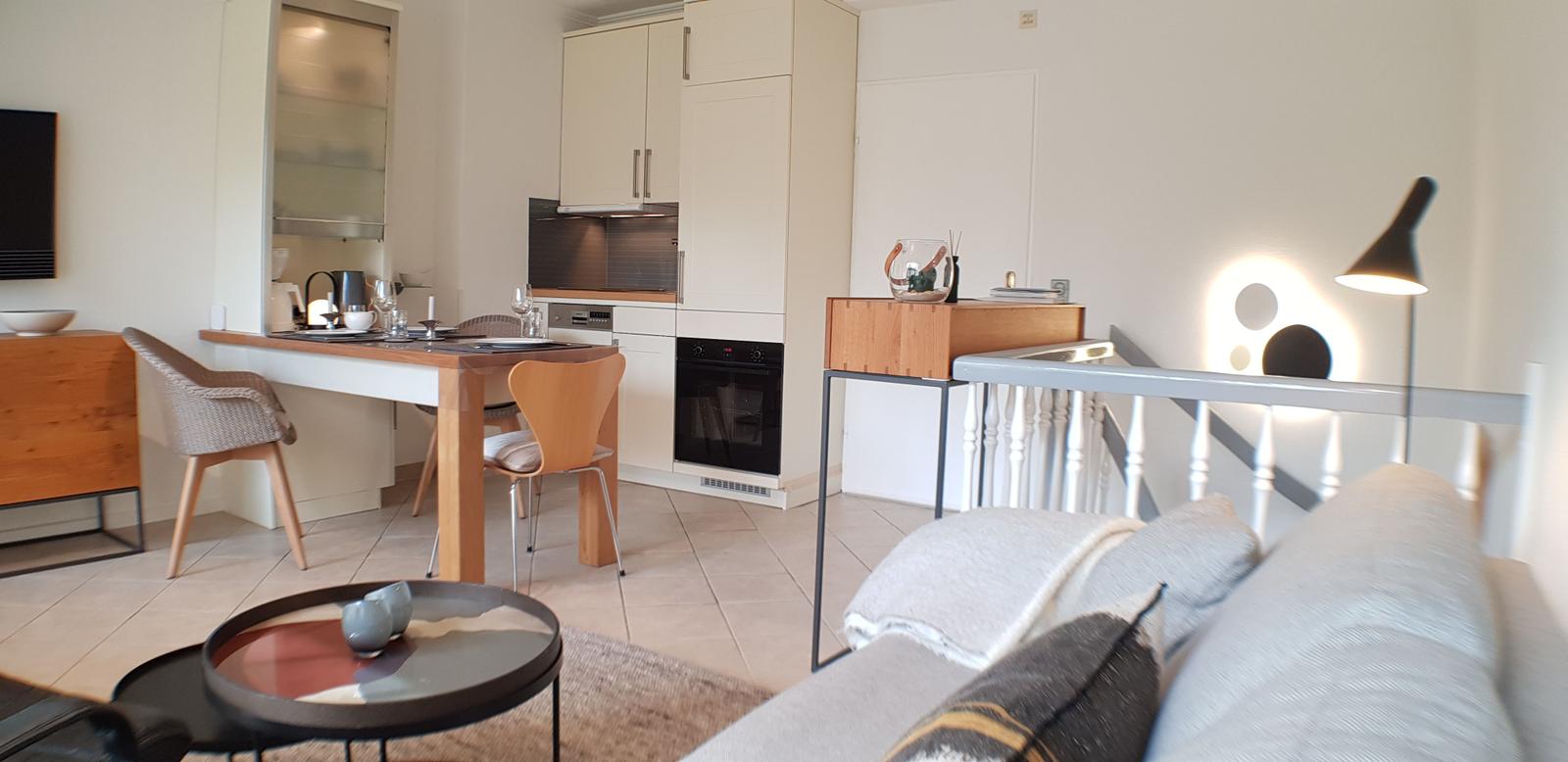 Wohnbereich mit Essbereich und Küche. Sofa, Tisch und Stühle sind sichtbar.