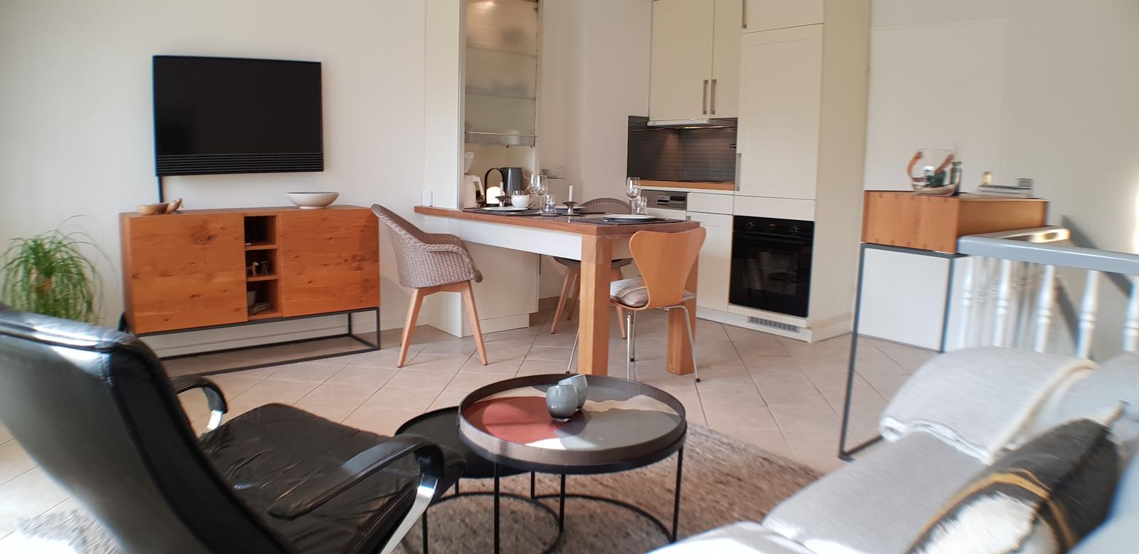 Wohn- und Essbereich mit Küchenzeile und TV. Holzmöbel und modernes Design.