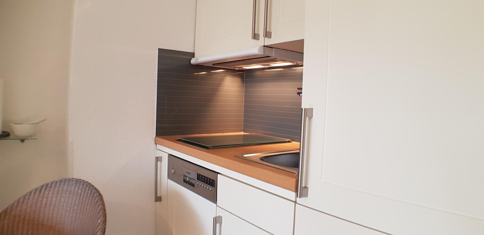 Küche mit Arbeitsplatte, Spüle und Dunstabzugshaube.