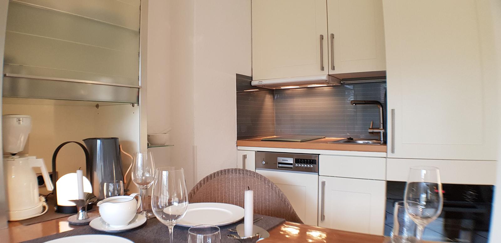 Küche mit Essbereich, weißen Schränken und Küchengeräten.